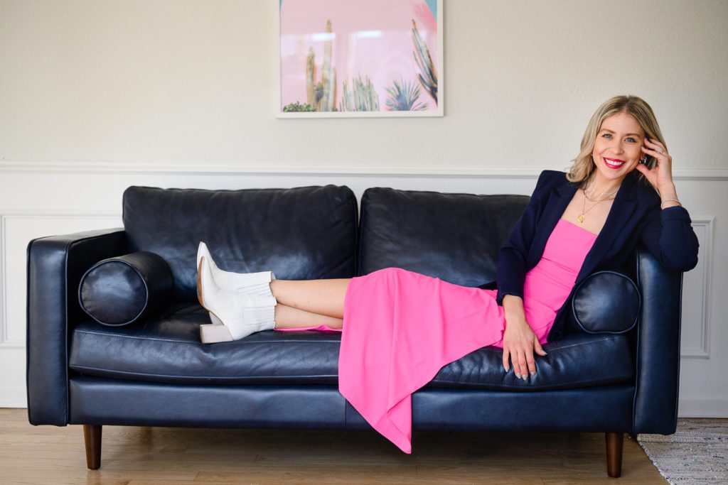 A woman lounging on her blue couch with a bright pink dress for her Denver Branding photos.