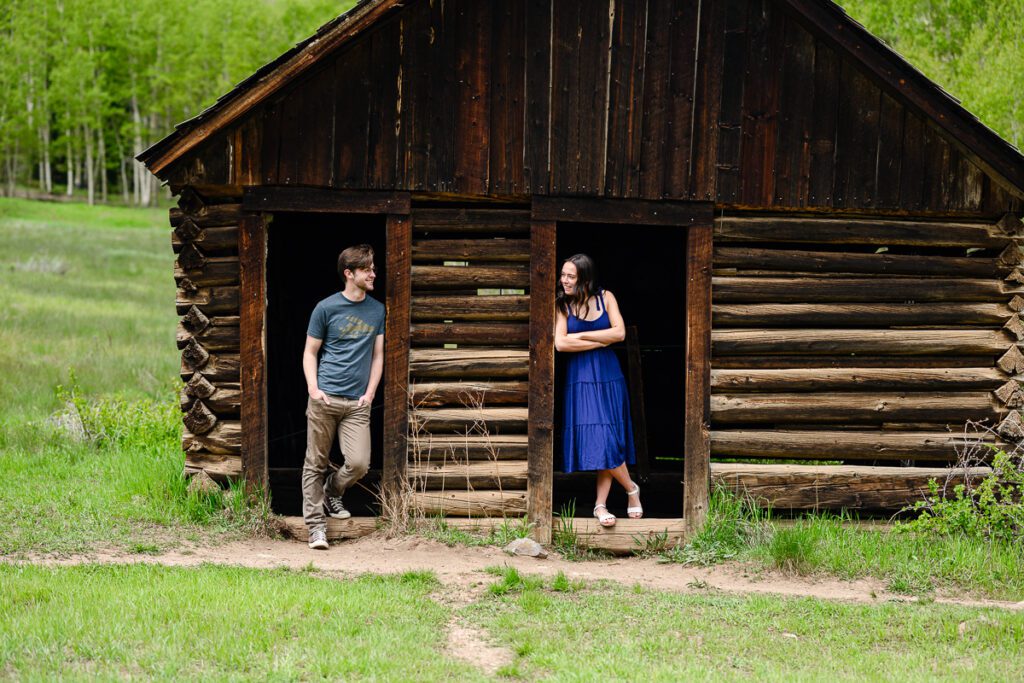 Two senior smile at each other in an old building at the Ashcroft ghost town in Aspen Colorado for their senior photos