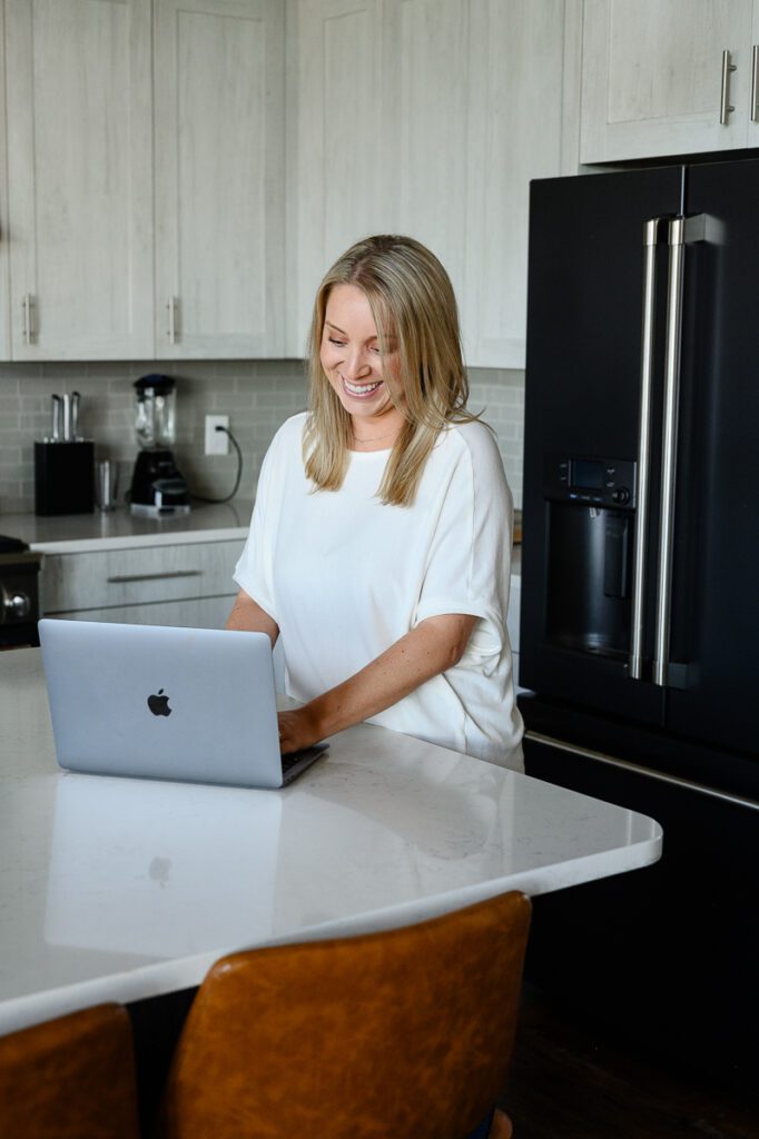 A woman smiling at her computer as a brand strategist captured by a Denver Branding Photographer