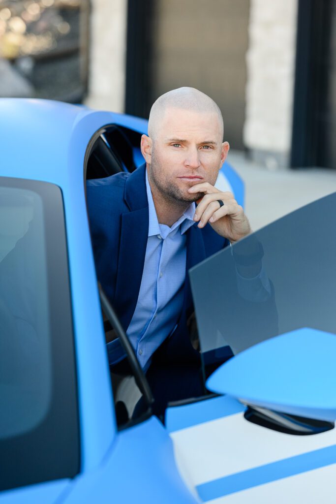 A man with striking blue eyes sits just outside of a blue Lamborghini as captured by a Denver branding photographer and brand consultant.