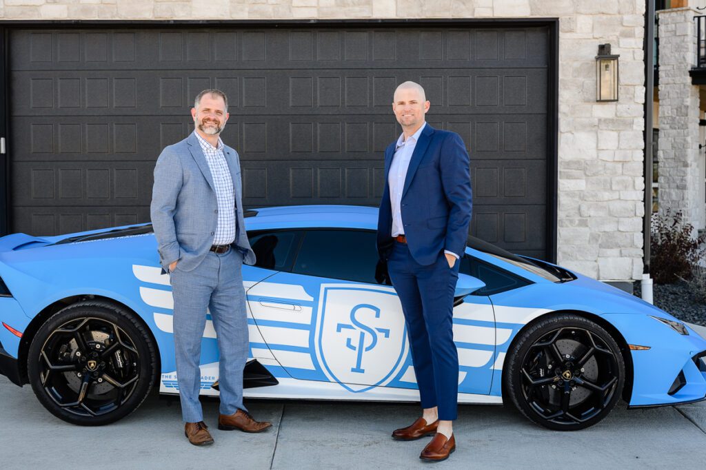 Two men posing with a blue Lamborghini with the letters ST on the door as captured by a Denver branding photographer and branding coach.