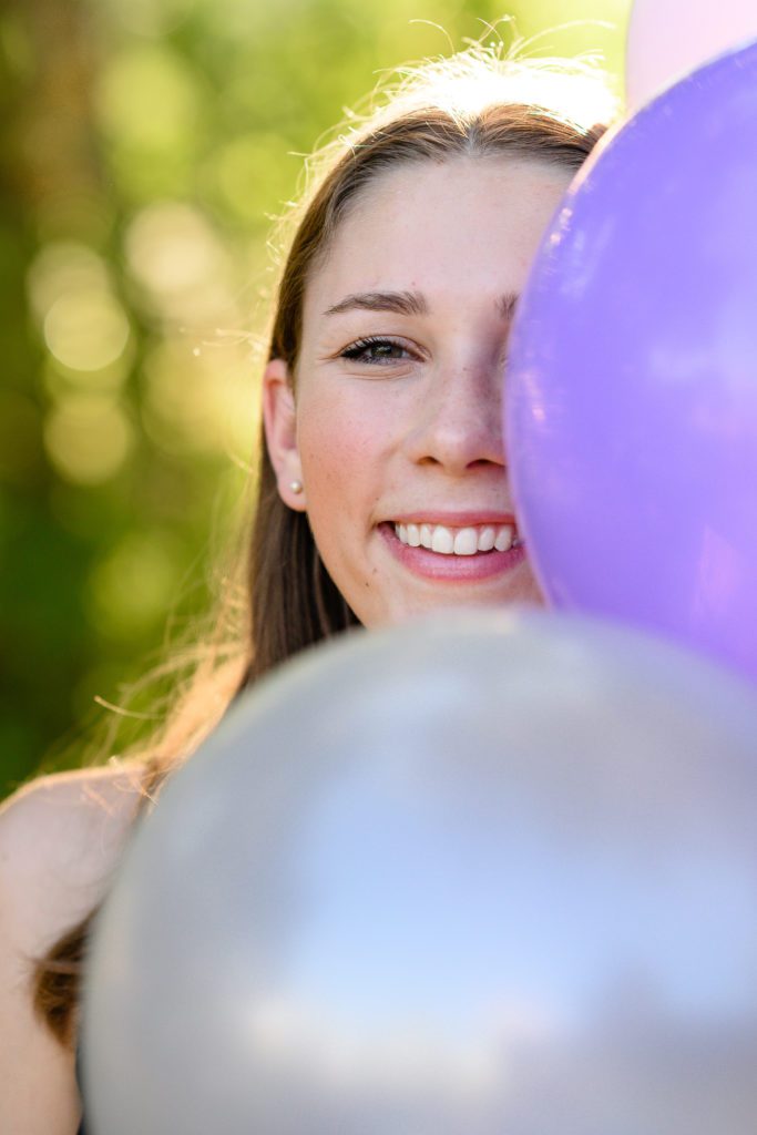 A girl bring purple balloons as a fun prop for her Denver senior pictures.