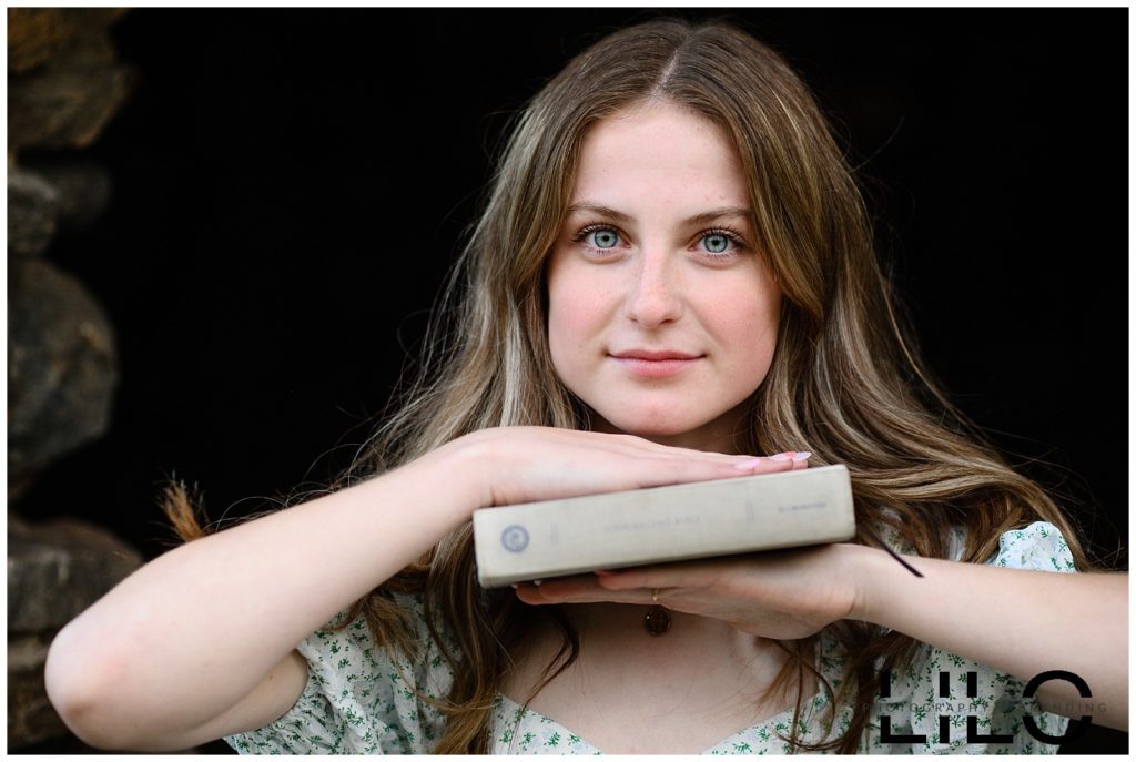 Denver Senior Photographer takes a picture of a young girl with green eyes holding a book.