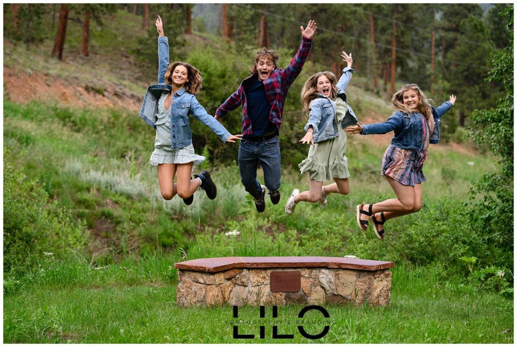 4 high school seniors in flannel shirts jumping with hands raised toward a Denver Senior Photographer