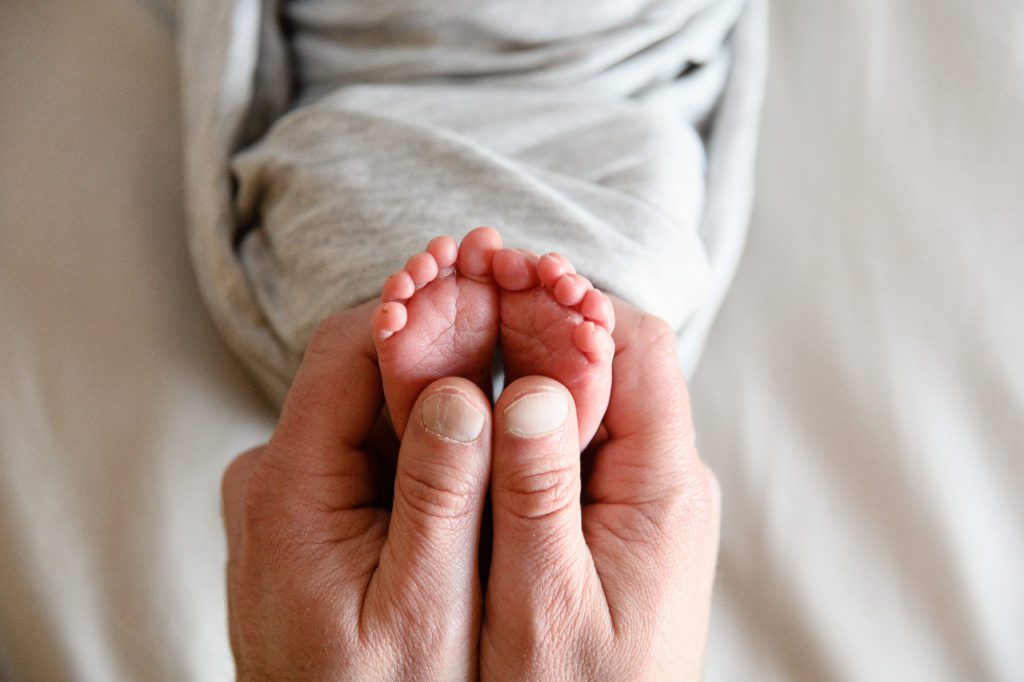 Denver Photographer takes a pictures of a dad holding the tiny toes of his newborn baby.