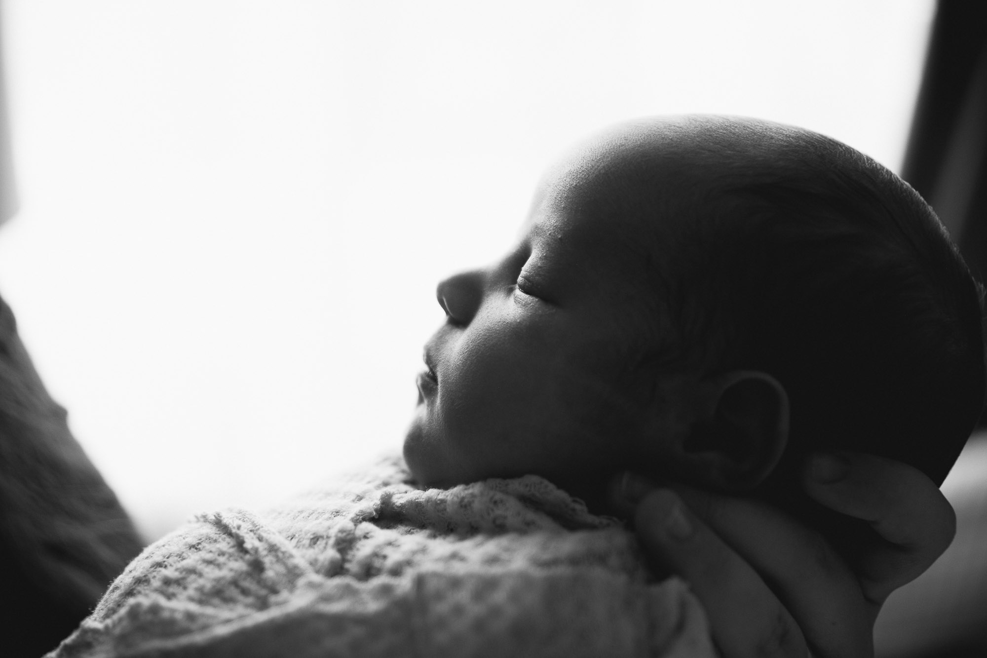 Denver photographer takes a black and white silhouette photo of a newborn baby's profile.