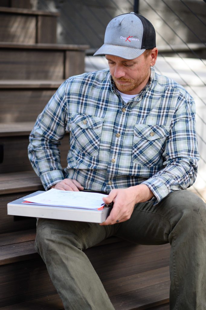 Denver Commercial Photographers showing a man reading blue prints of a deck.