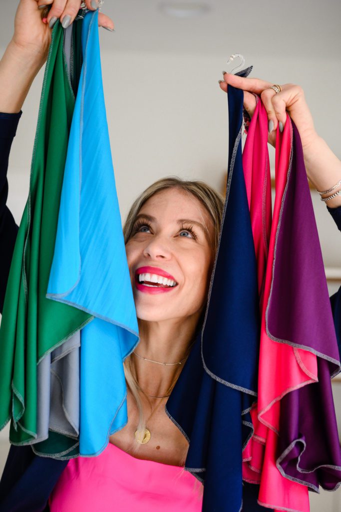 A blonde woman looking up at colored scarves and smiling for a Denver commercial photographer.
