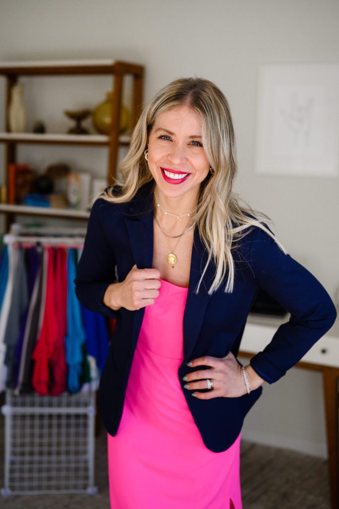 A blonde woman holding her blue blazer and smiling for a headshot a denver commercial photographer for her branding photos.