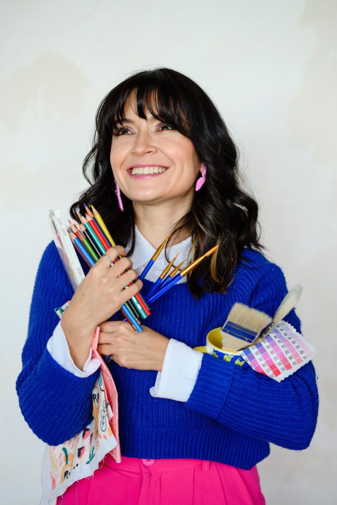 Denver Commercial Photographers capture a woman in a blue sweater holding art supplies for her branding photos.
