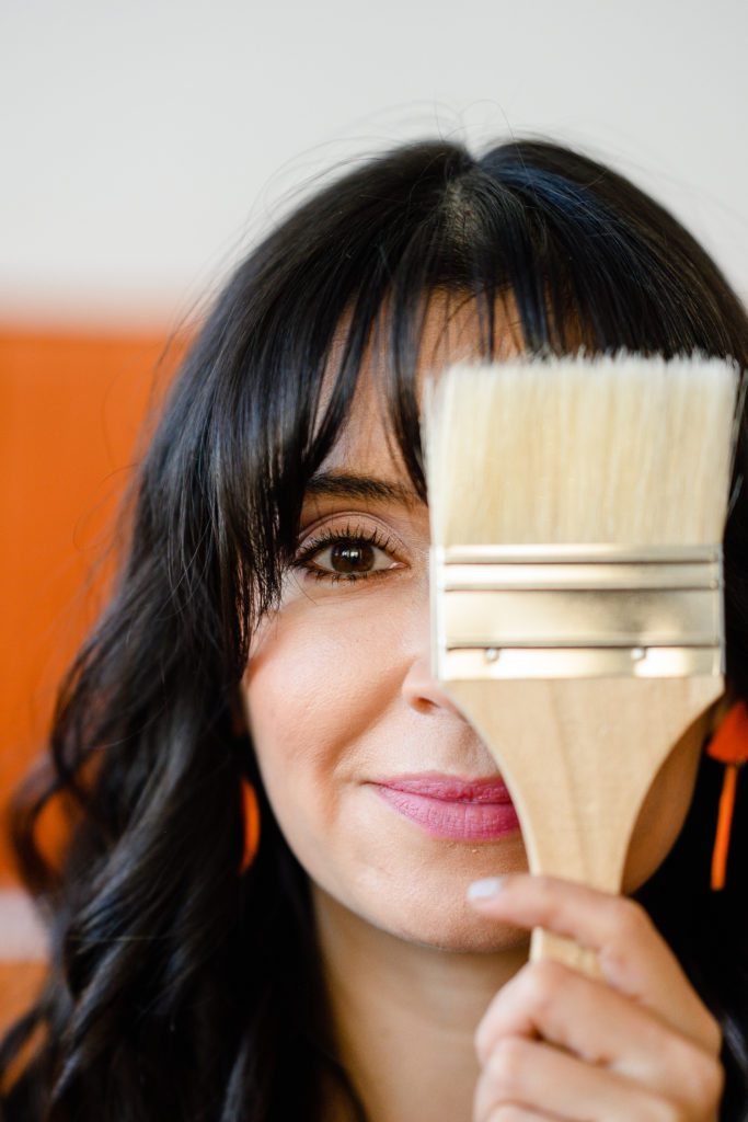 Denver Commercial Photographers captures woman with paint brush covering one eye.
