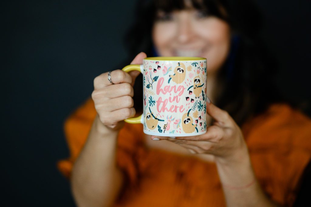 Denver Commercial Photographers captures branding photos of woman wearing an orange dress holding a mug that says hang in there.