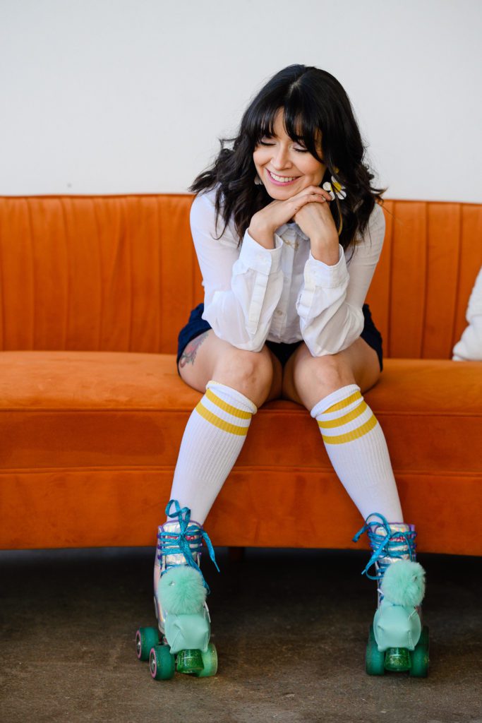 Denver Commercial Photographers captures personal branding photos of woman on orange couch wearing teal roller skates.