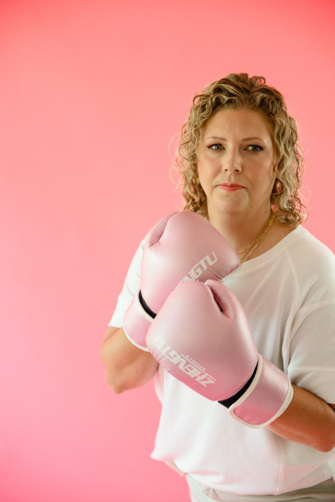 A blonde woman with pink boxing gloves looking fiercely at a Denver Commercial Photographer.