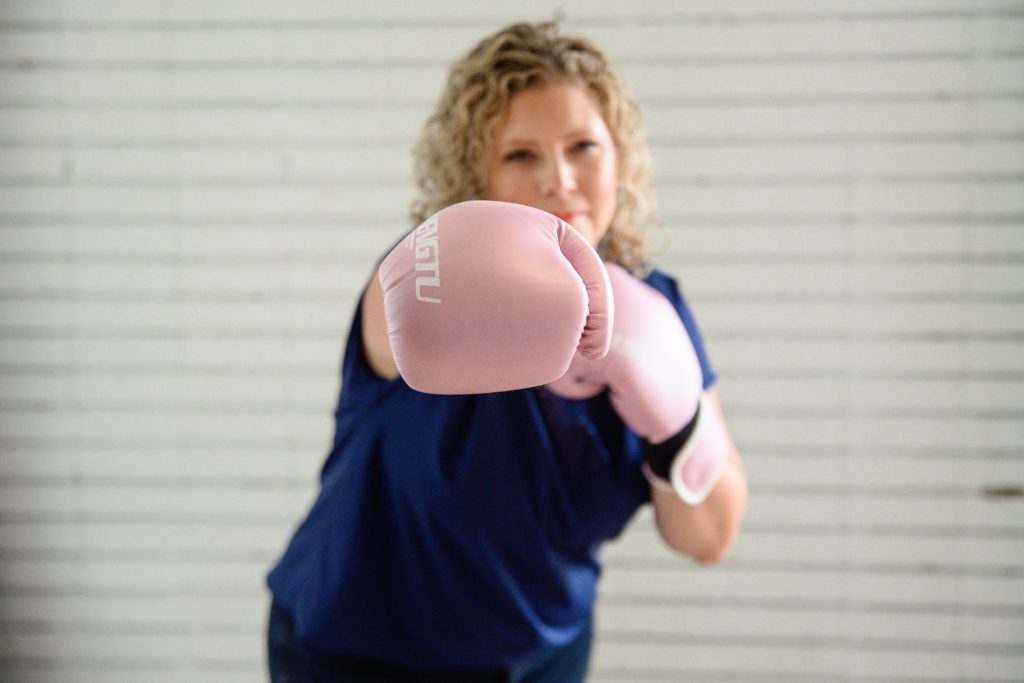 Denver Commercial Photographers captures woman wearing pink boxing gloves.