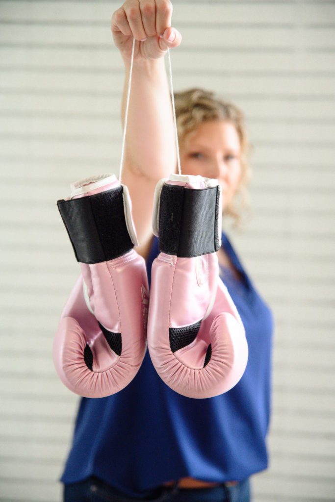 Denver Commercial Photographers captures woman holding up pink boxing gloves for her personal branding photos.