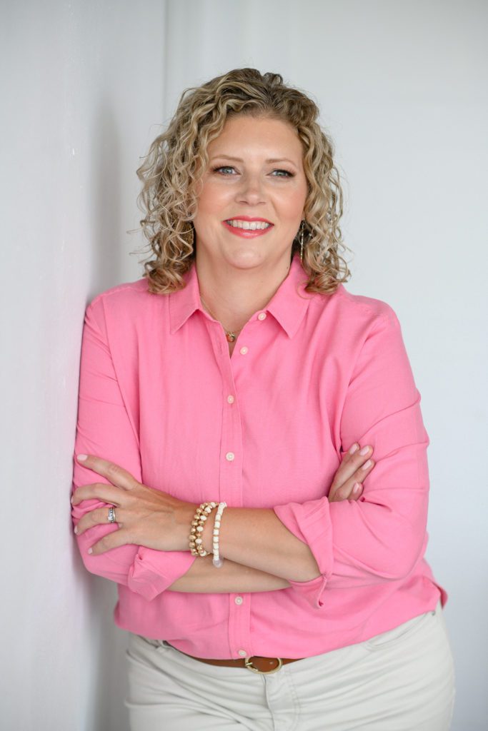 Denver Commercial Photographers captures woman wearing bright pink top with beautiful blonde curly hair.
