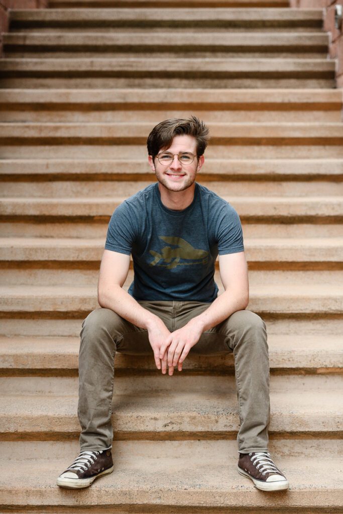 Senior guy sitting on stairs in Aspen for his Colorado Mountain senior pictures