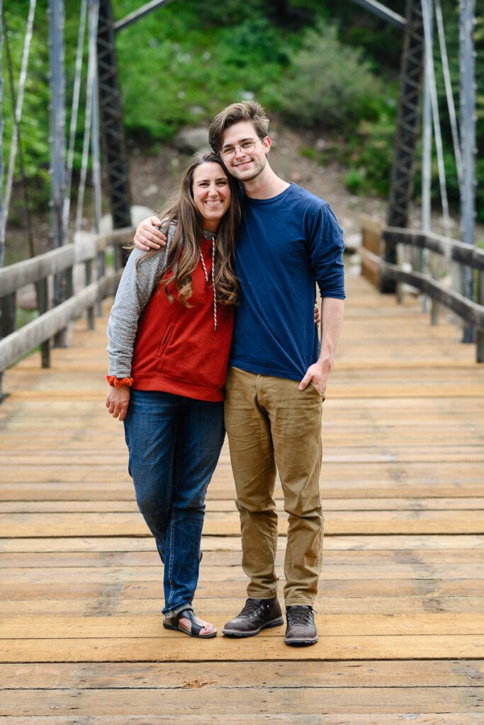 Mom and son stand on a bridge in Aspen colorado smiling at a Colorado senior photographer