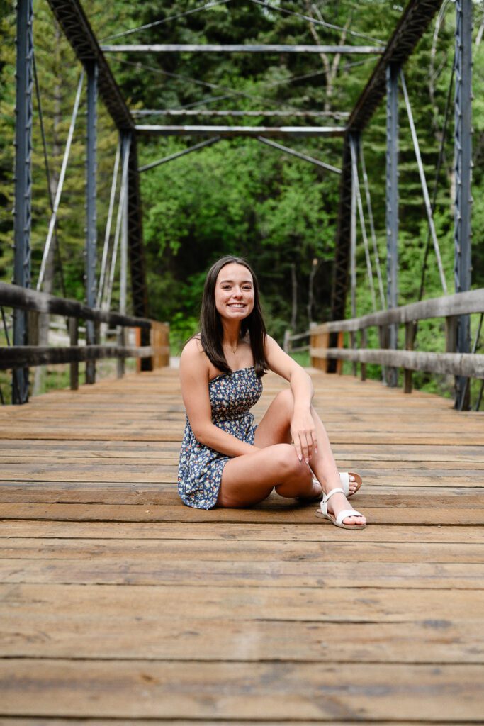 A girl sits on a bridge for her senior pictures in Aspen colorado as captured by a Denver Senior Photographer