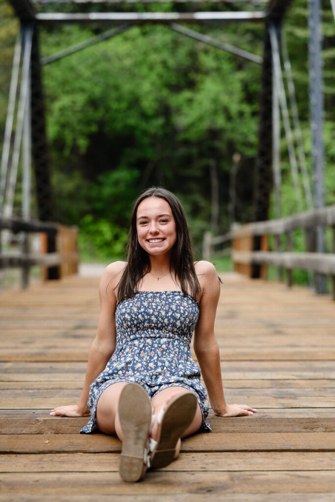 A girl sits on a bridge for her senior pictures in Aspen colorado as captured by a Denver Colorado Senior Photographer