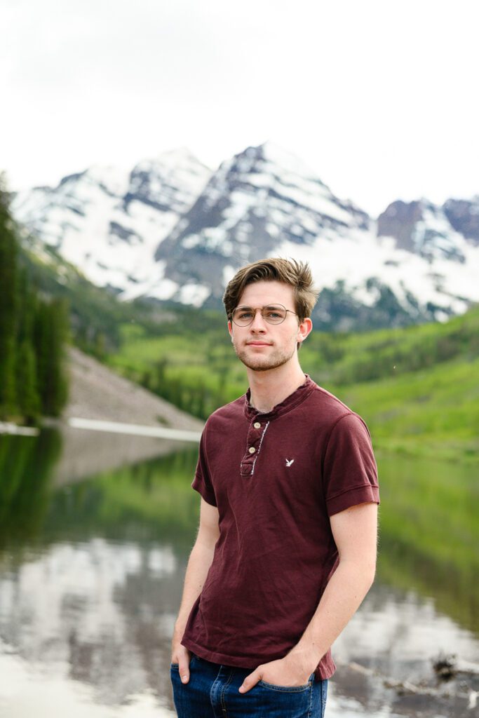 Senior guy standing in front of the iconic Aspen Maroon Bells for his Colorado senior pictures