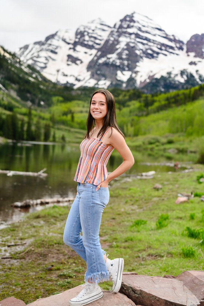 A cute senior girl smiling at a Denver senior photographer standing in front of the Maroon Bells in Aspen Colorado