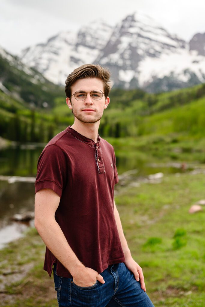A senior guy stands in front of the iconic Maroon Bells in Aspen Colorado for his Colorado Mountain Senior Pictures