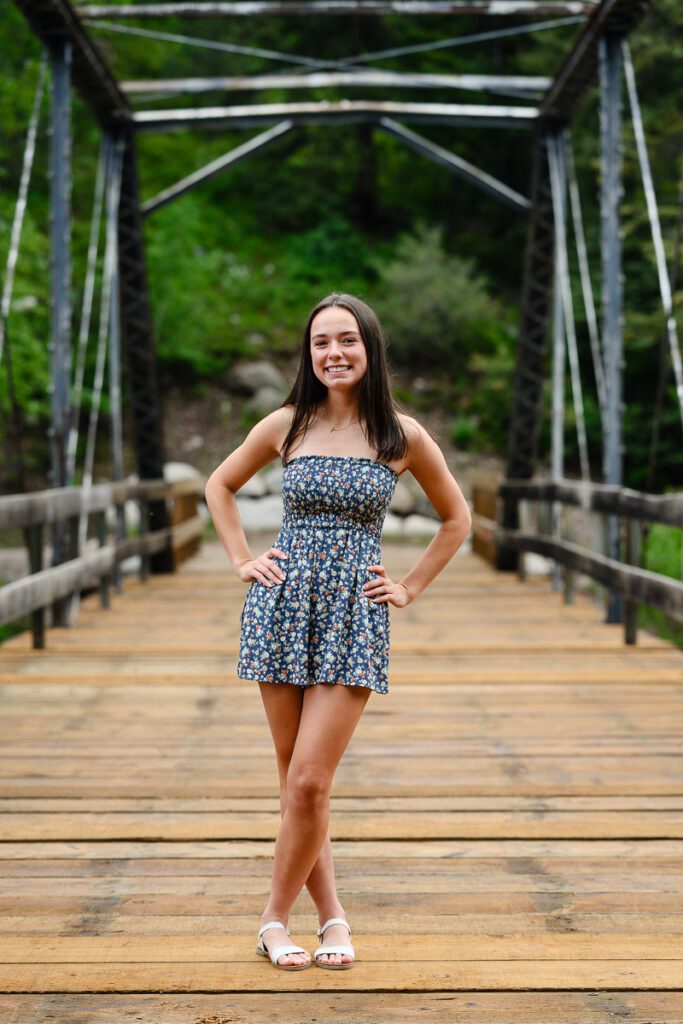 A denver girl stands on a bridge in Aspen Colorado for her Colorado senior pictures