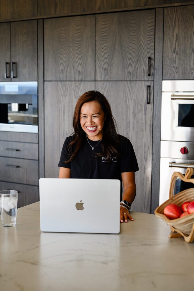 Denver commercial photographer captures a woman doctor smiling at her computer in a casual, home enviornment.