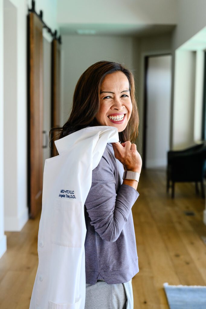 A doctor with her lab coat thrown over her shoulder, smiles at her Denver commercial photographers.