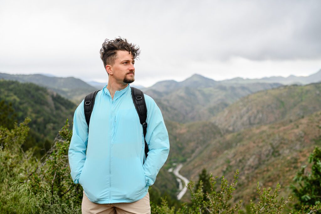 A man wearing a lightweight jacket in front of a mountain backdrop posing for Denver Branding Photos.
