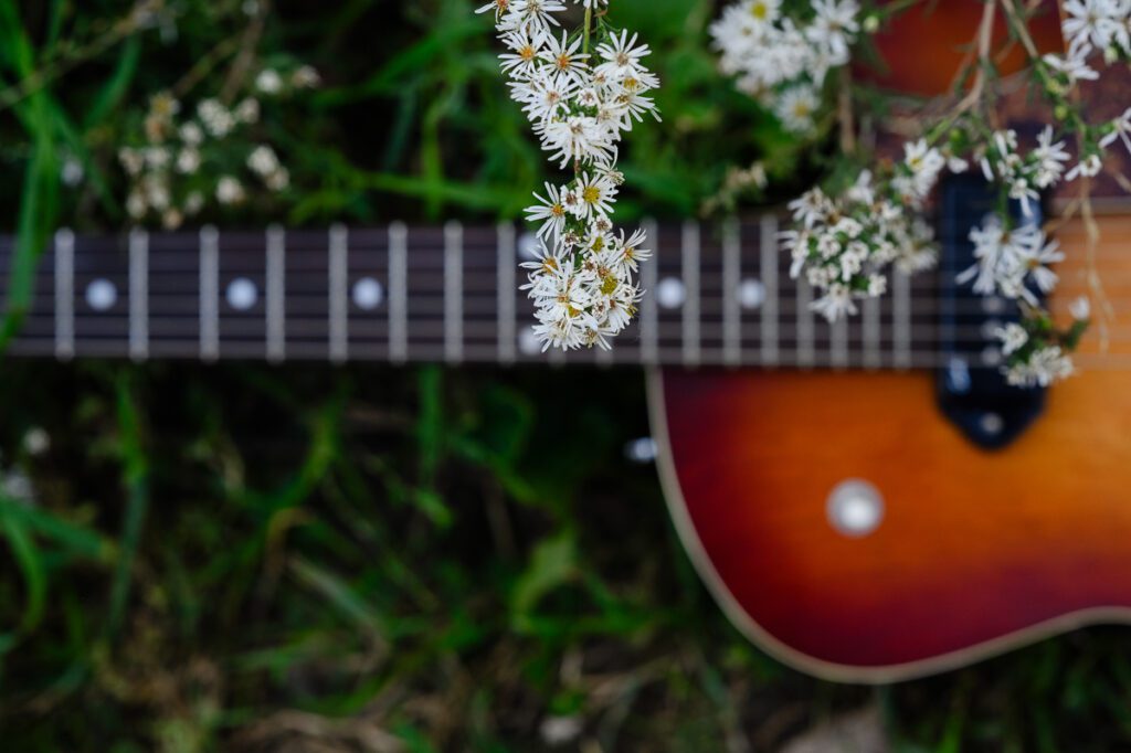 A closeup of a guitar with little white flowers on it as captured for a musician for his Denver Branding Photography by a Denver branding photographer