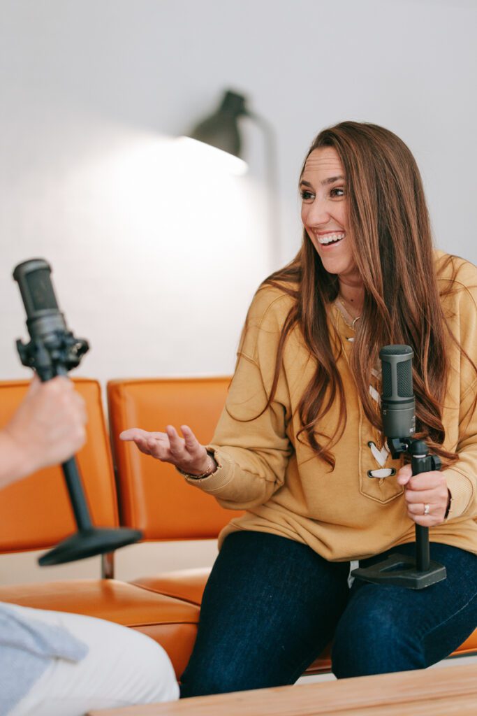 A woman holding a podcast mic for her Denver branding photos for a Denver commercial photographer and Denver branding photographer and branding coach and branding strategist.