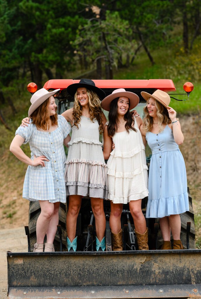 Denver photographer captures four senior girls standing on a red tractor.