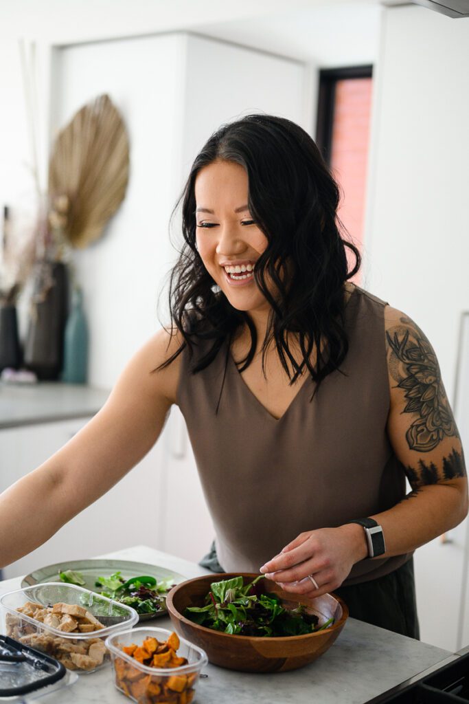 A woman smiling and organizing healthy food for her branding photos for a nutrition company.