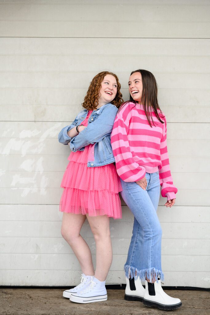 2 young seniors in Denver standing in bright pink and orange smiling at a Denver branding photographer and brand strategist.