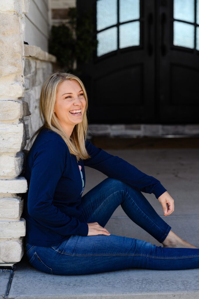 A woman sitting on the porch laughing at a Denver branding photographer and brand consultant.