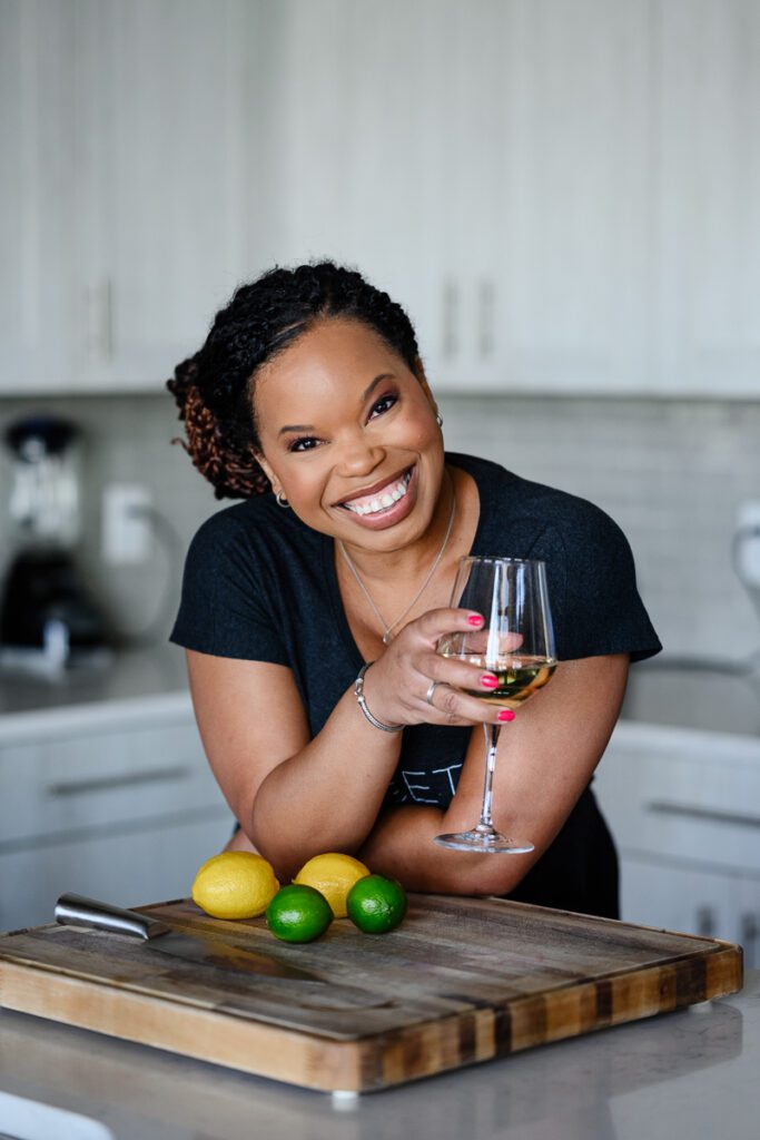 A black business owner standing in the kitchen holding a glass of wine for her Denver branding photos for a Denver Branding photographer and branding strategist.