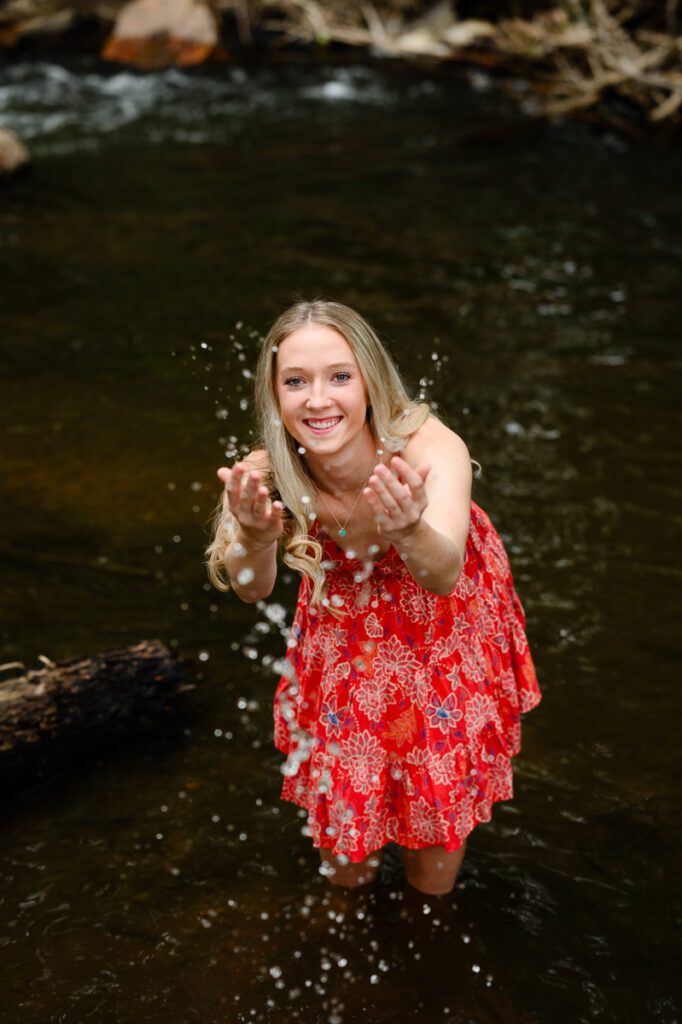 A Denver senior girl throwing water at her Denver photographer and branding strategist.