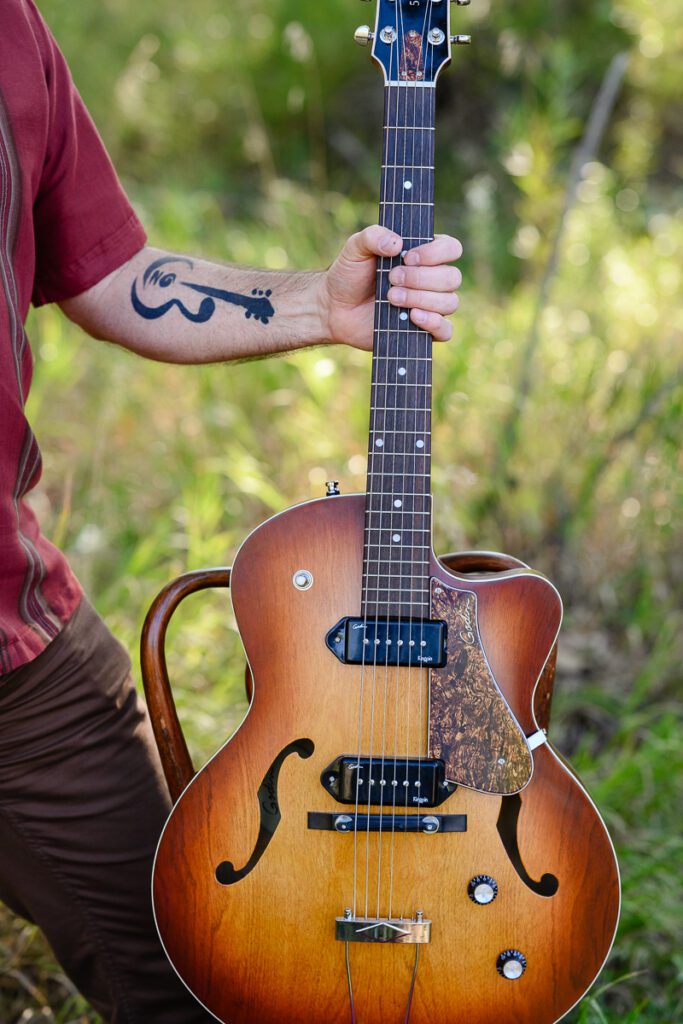 A closeup of a guitar and a man with guitar tattoo captured by a Denver Branding photographer and brand strategist.