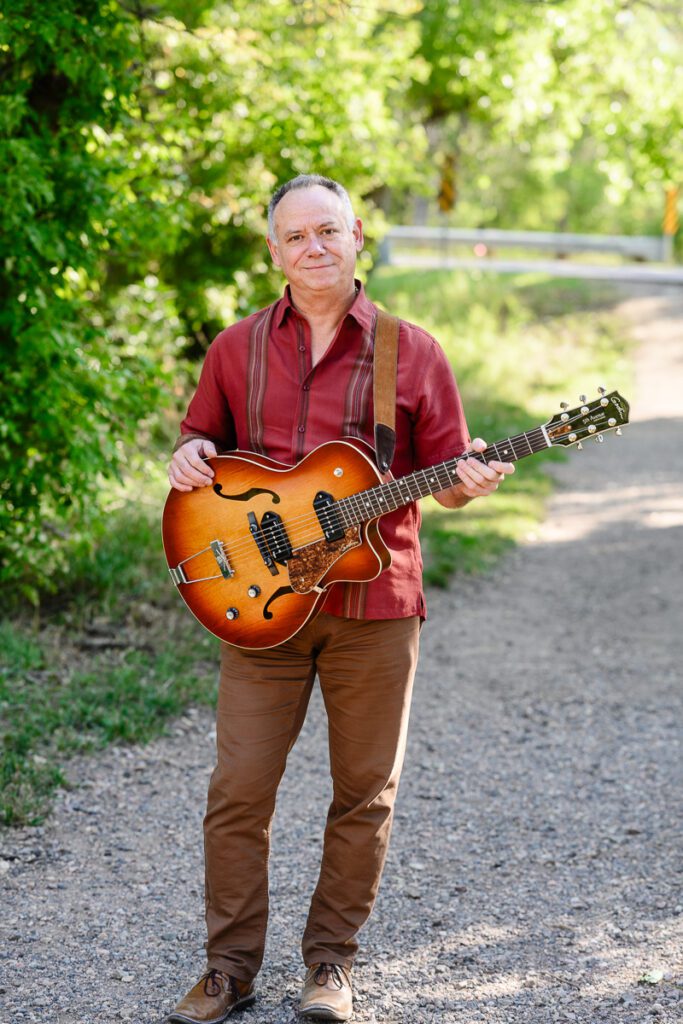 A Denver branding photographer and brand strategist captures a musician standing on a path holding a guitar for his branding photos.