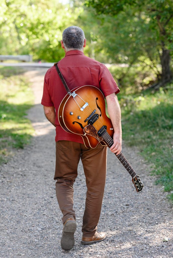 A Denver branding photographer and brand strategist captures a musician walking away from the camera holding a guitar for his branding photos.