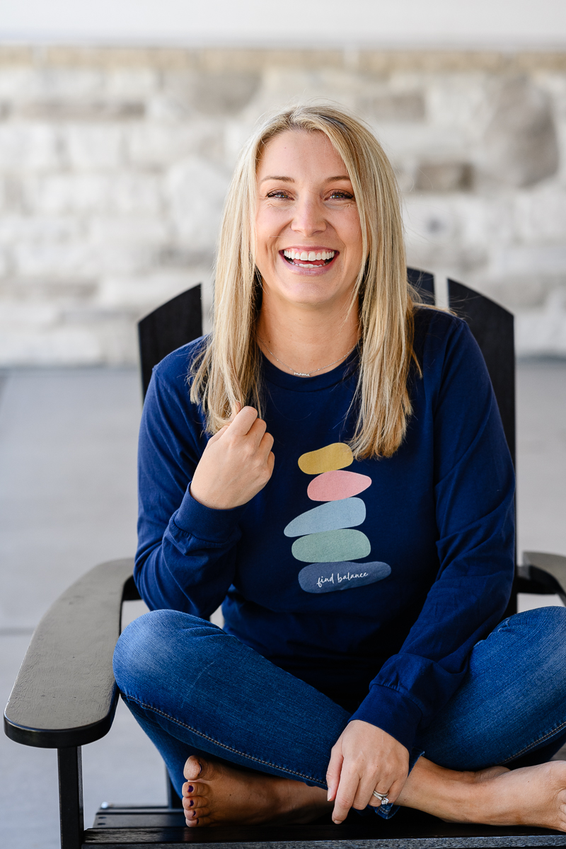 A blonde small business owner sitting criss cross smiling at a Denver branding photographer and brand strategist.