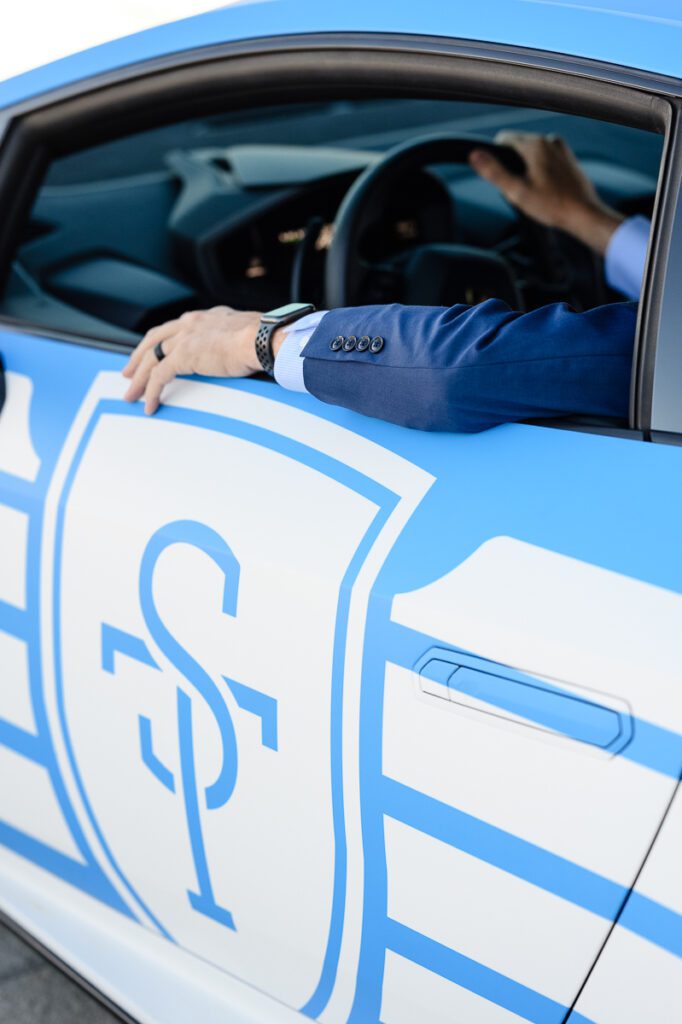 An arm sitting on a blue Lamborghini with the letters ST on the door as captured by a Denver branding photographer and branding coach.
