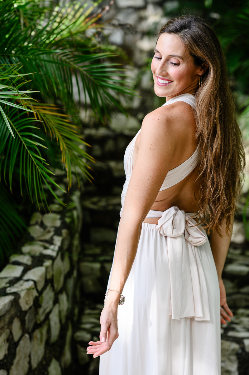 Woman looks down her shoulder and she turns her back to the camera and smiles on a stone path at a resort in Costa Rica with brand photographer while Choosing Brand Colors