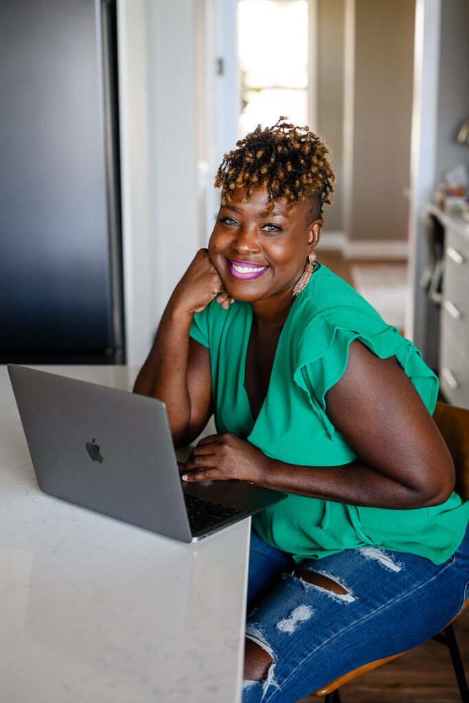 A black small business owner sits by her computer as she is working on her brand strategy with her brand coach.