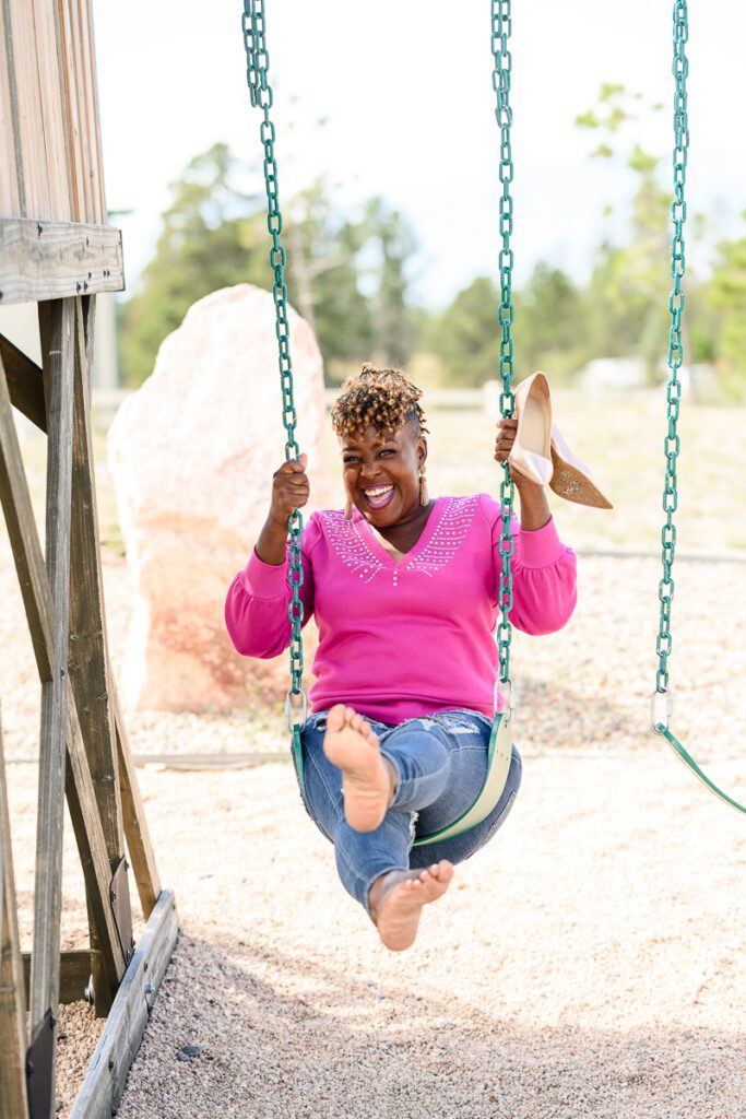 A fun picture of a black woman small business owner on a swing for her brand strategist.