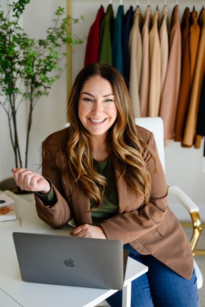 A fashion influencer sits at her desk smiling for her branding photos for her Denver commercial photographers.