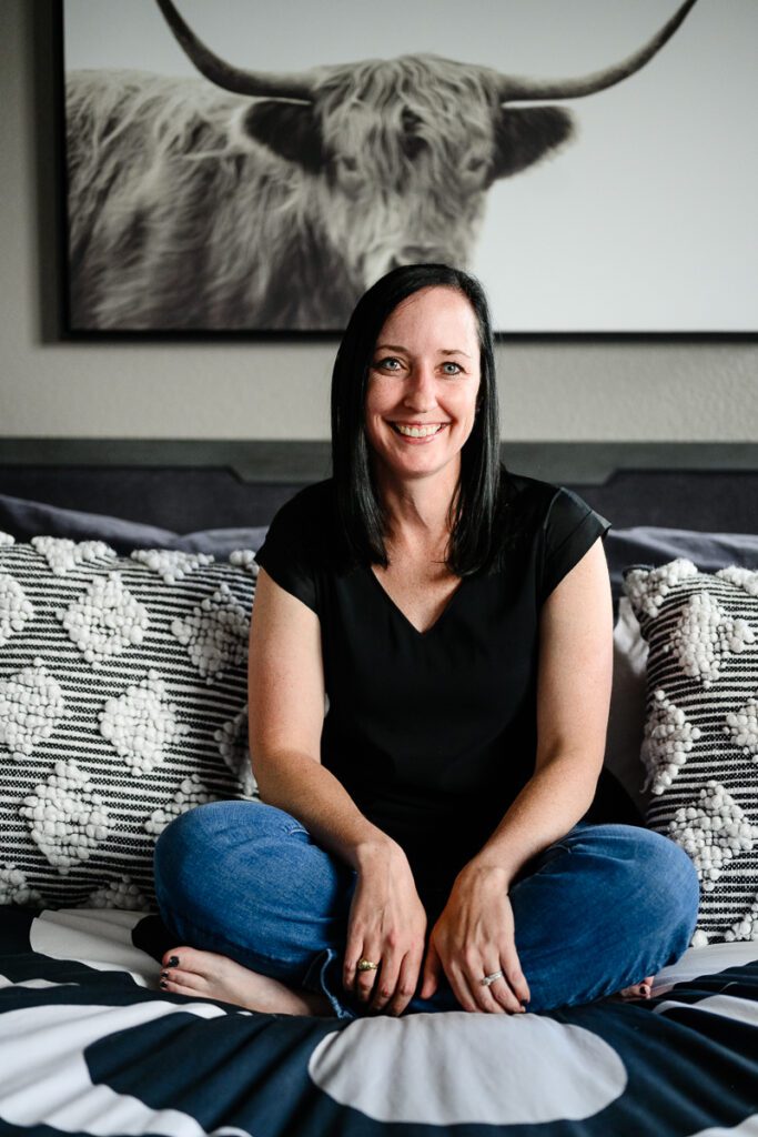 A Denver branding photographer captures a woman sitting on a bed for her Denver Branding photos.